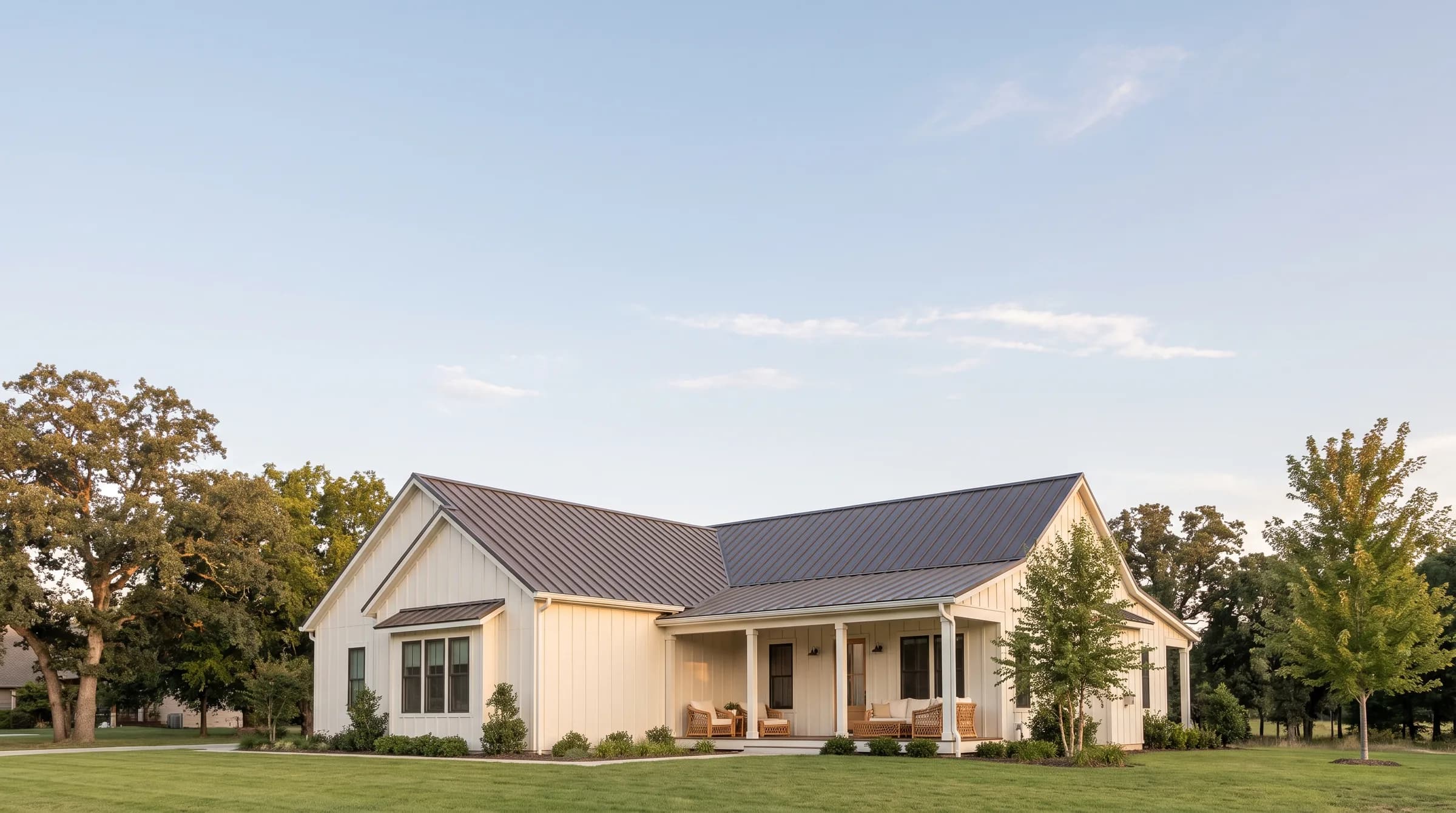 A white farmhouse-style home under a wide, clear evening sky